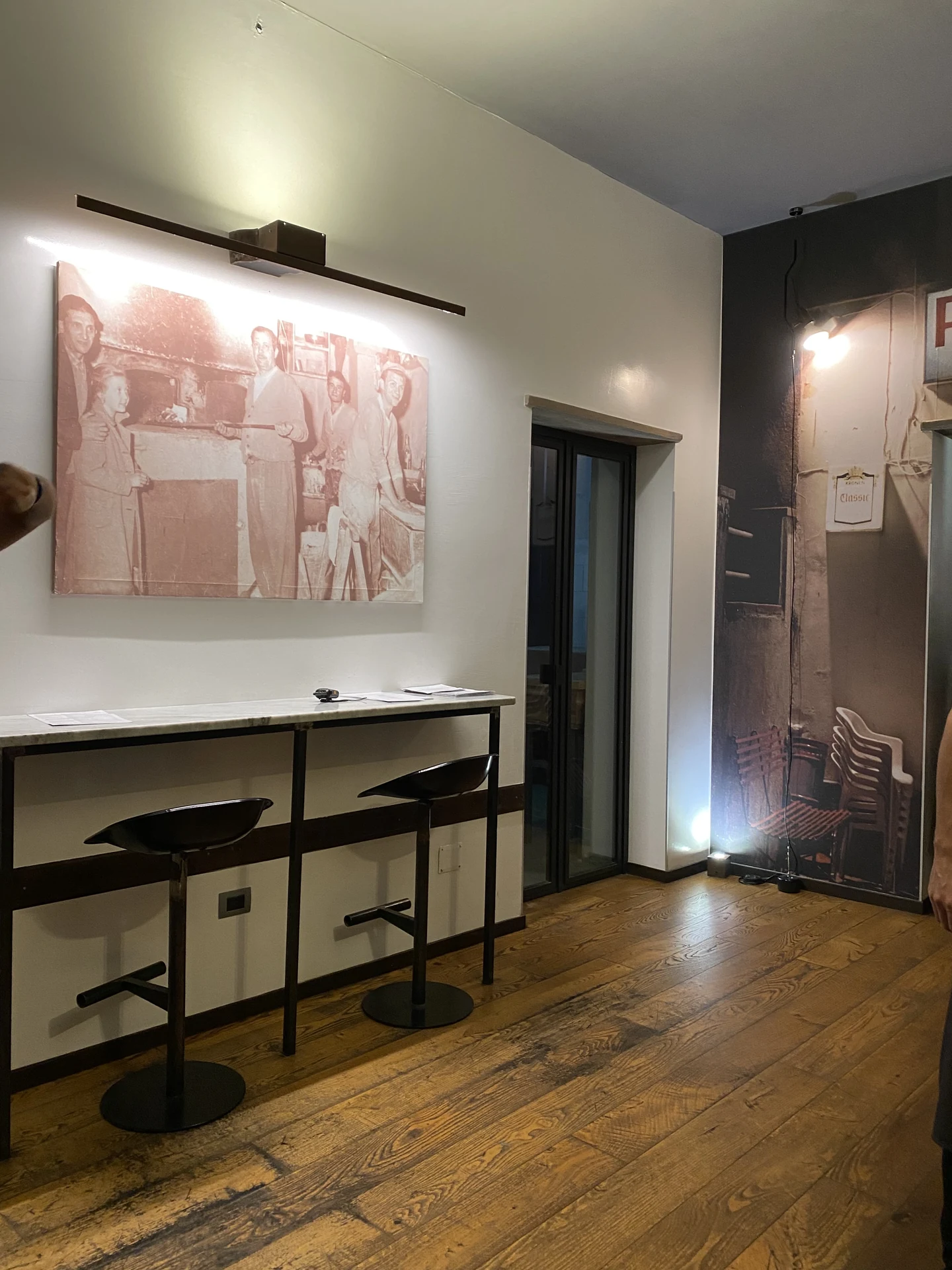 Tavolo degustazione con sgabelli e quadro storico illuminato a regola d'arte da barra lineare a parete