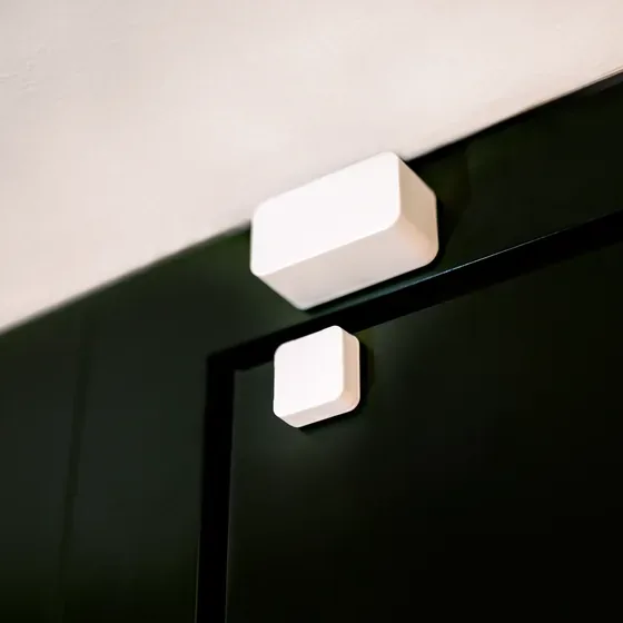Nuki Door Sensor e magnete applicati sul telaio superiore di una porta scura