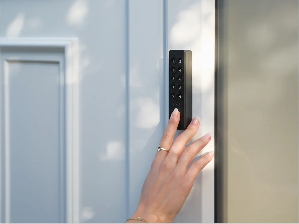 Mano che digita il codice sul tastierino Nuki Keypad 2 NFC montato accanto a una porta